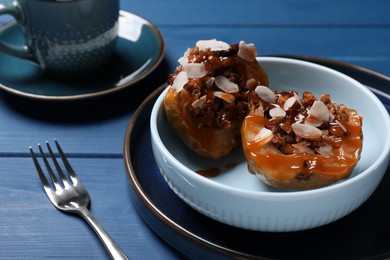 Photo of Delicious baked apple halves with nuts and caramel served on blue wooden table, space for text