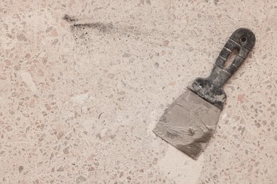Photo of Metal spatula on floor, top view with space for text. Tiles installation process