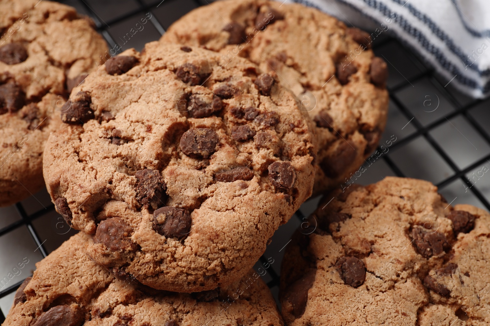 Photo of Cooling rack with delicious chocolate chip cookies on white table, closeup