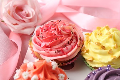 Photo of Delicious cupcake with bright cream on pink fabric, closeup