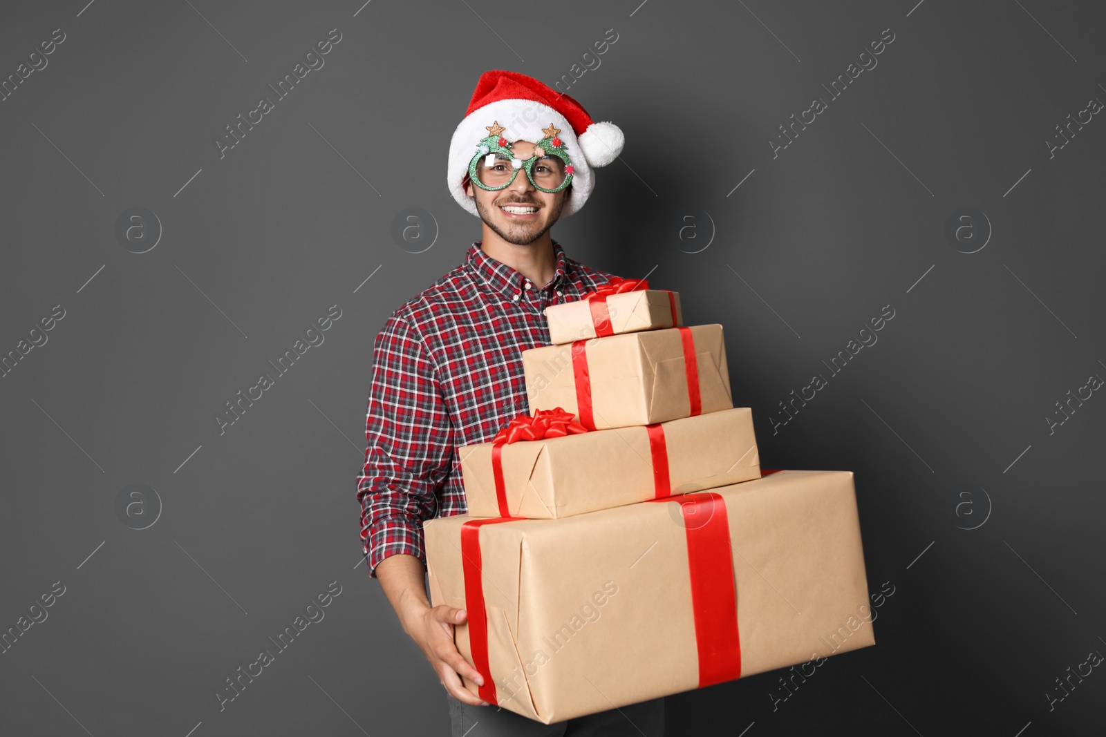 Photo of Young man with Christmas gifts on grey background