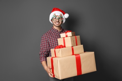 Photo of Young man with Christmas gifts on grey background