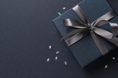 Photo of Beautiful gift box and confetti on black background, flat lay. Space for text