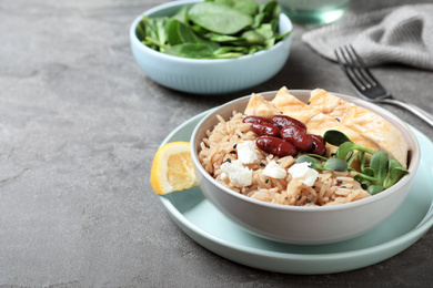 Photo of Tasty rice with beans and meat served on grey table