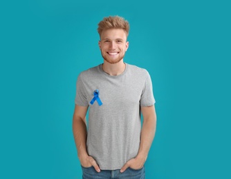 Young man with blue ribbon on turquoise background. Urology cancer awareness