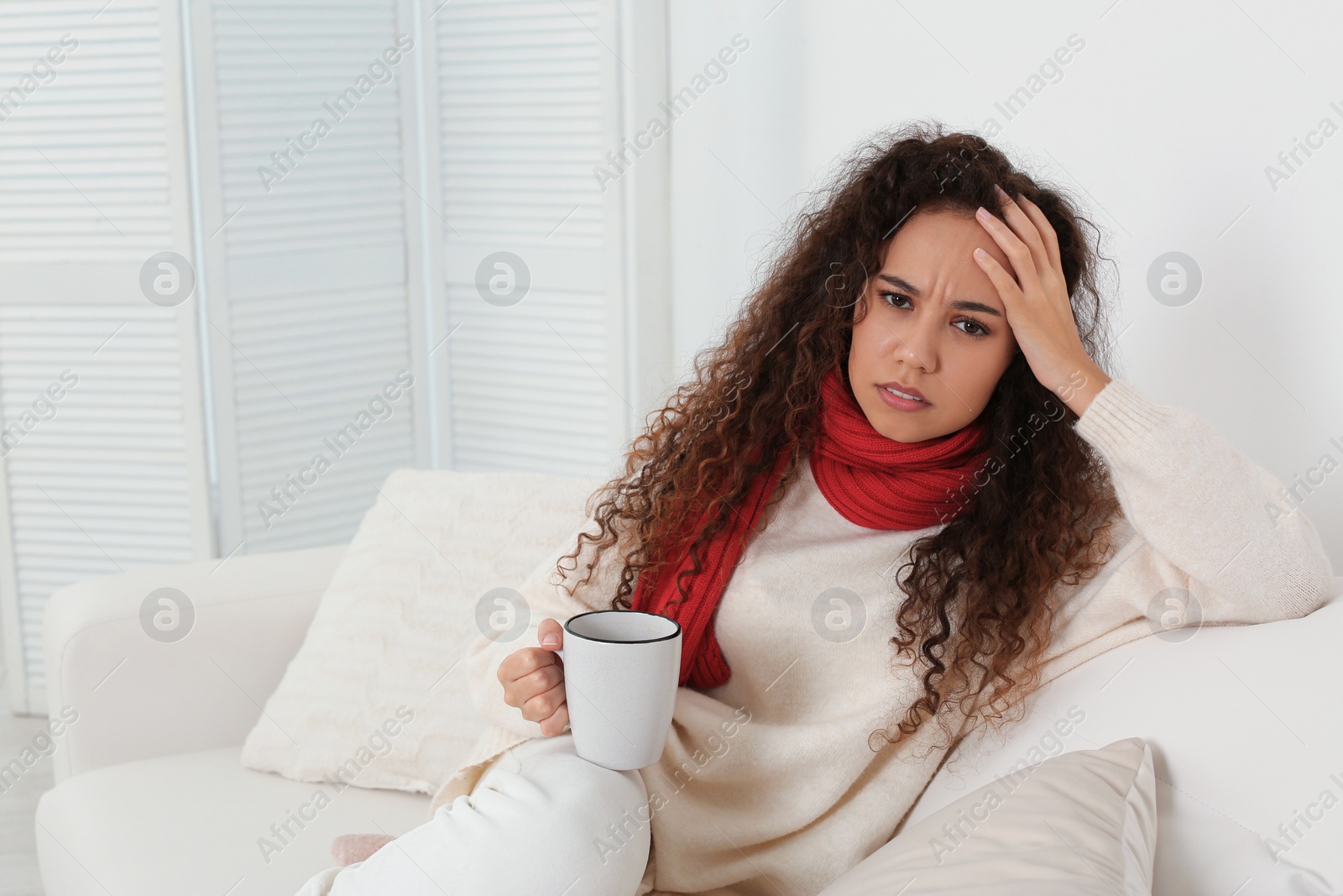 Photo of Sick African American woman with cup of hot drink at home