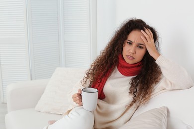 Photo of Sick African American woman with cup of hot drink at home