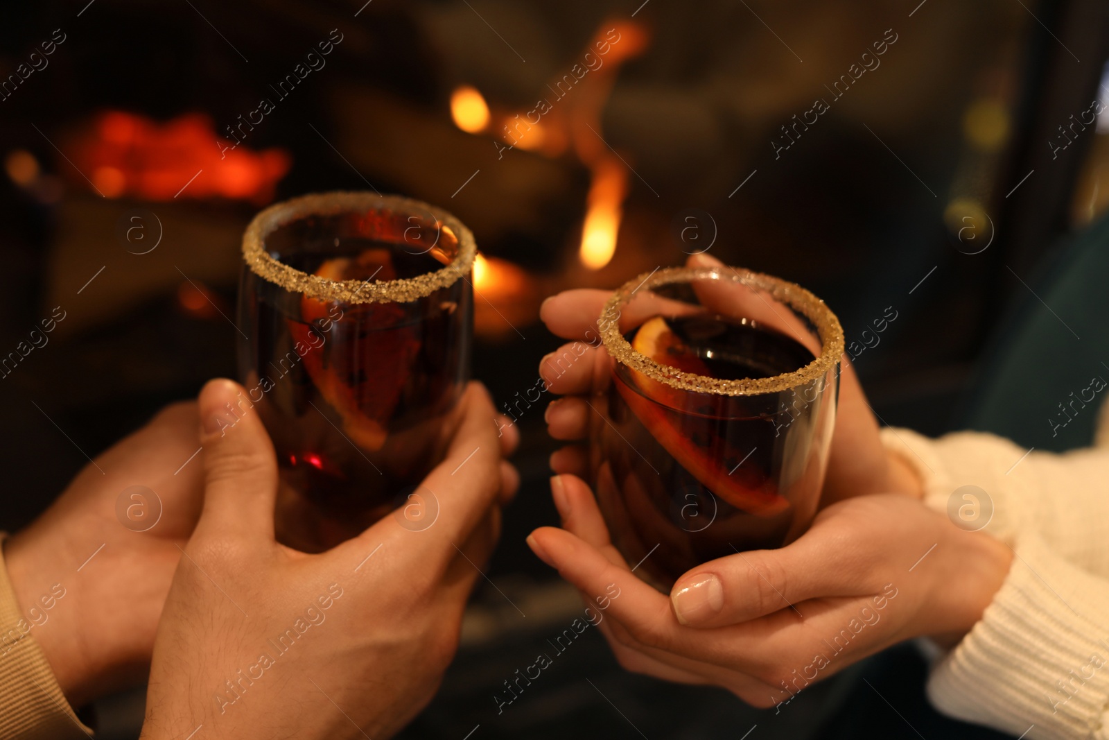 Photo of Couple with tasty mulled wine near fireplace indoors, closeup