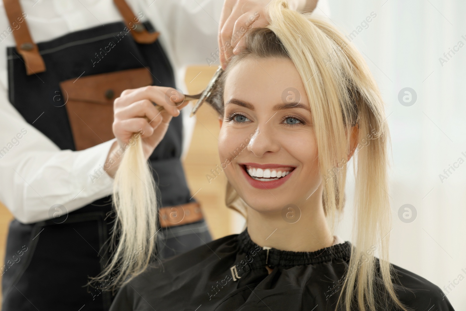 Photo of Hair styling. Professional hairdresser working with happy client indoors, closeup