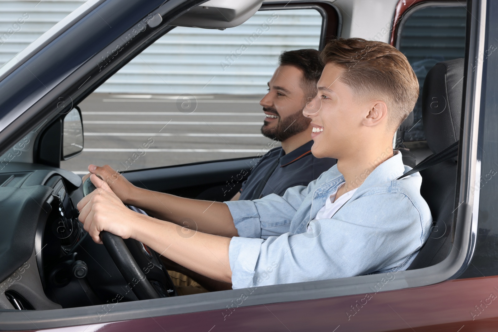 Photo of Driving school. Happy student during lesson with driving instructor in car