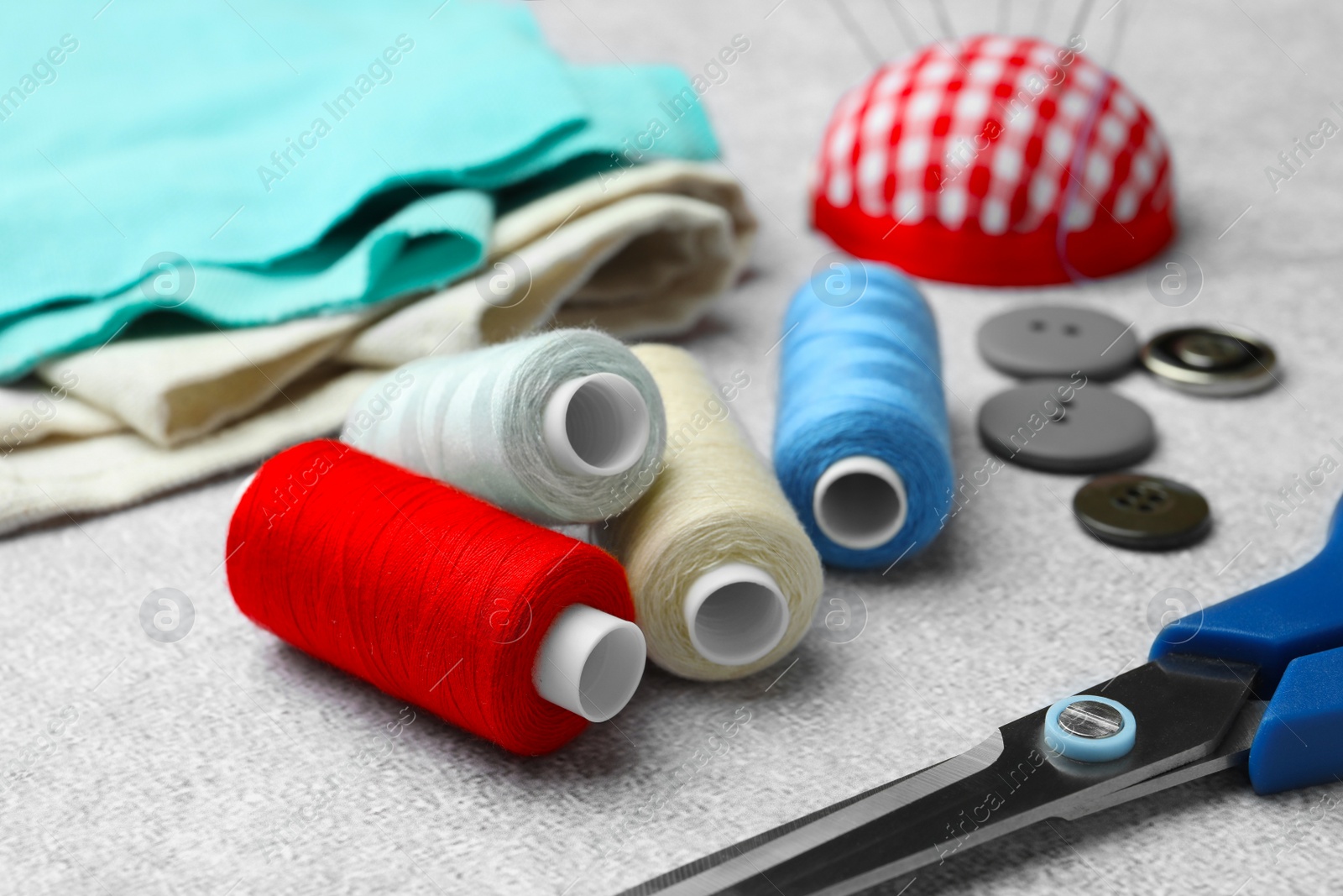 Photo of Spools of threads and sewing tools on white background, closeup