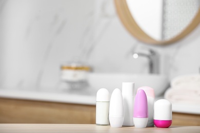 Photo of Different female deodorants on wooden table in bathroom, space for text