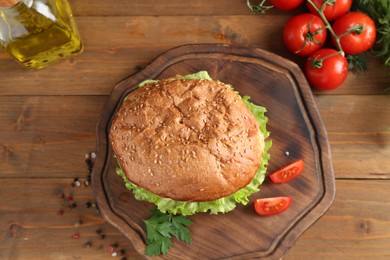 Photo of Delicious vegetarian burger served on wooden table, flat lay