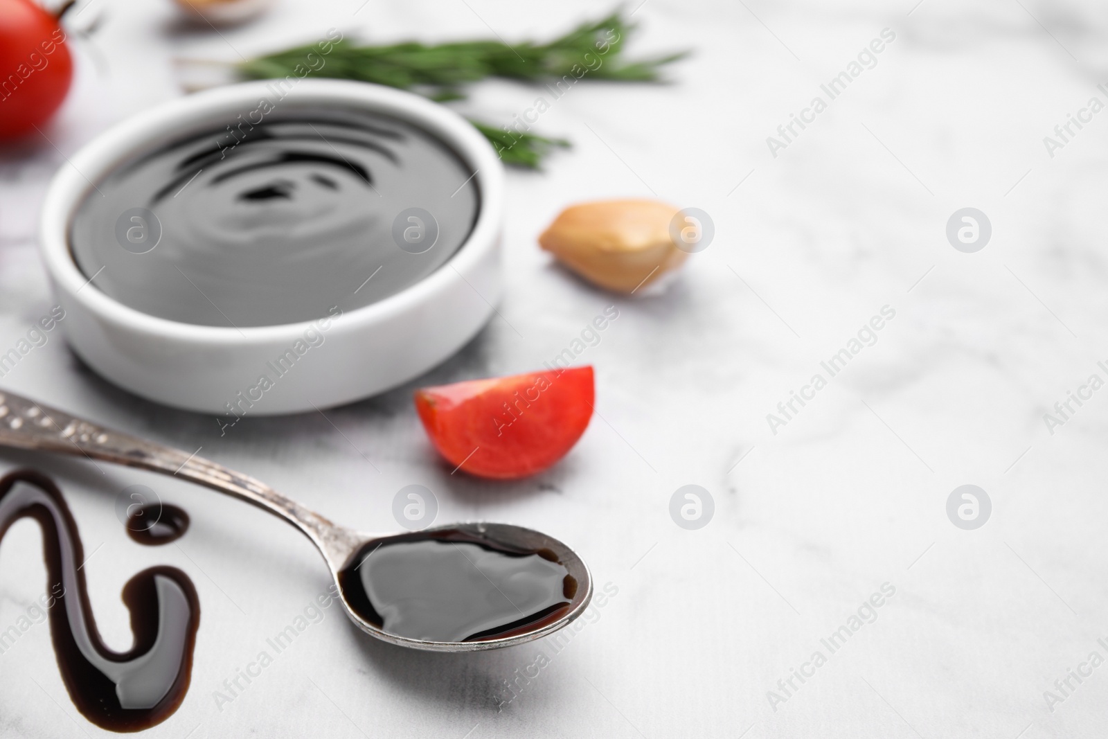 Photo of Organic balsamic vinegar and cooking ingredients on white marble table, closeup. Space for text