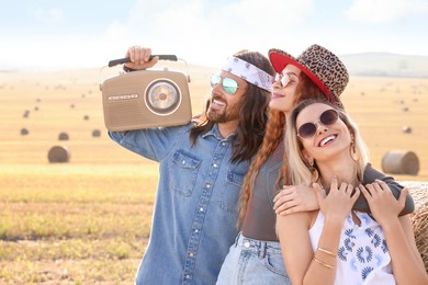 Photo of Happy hippie friends with radio receiver in field