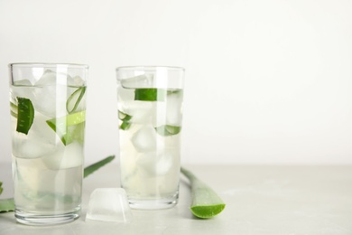 Photo of Fresh aloe drink and leaves on light table, space for text