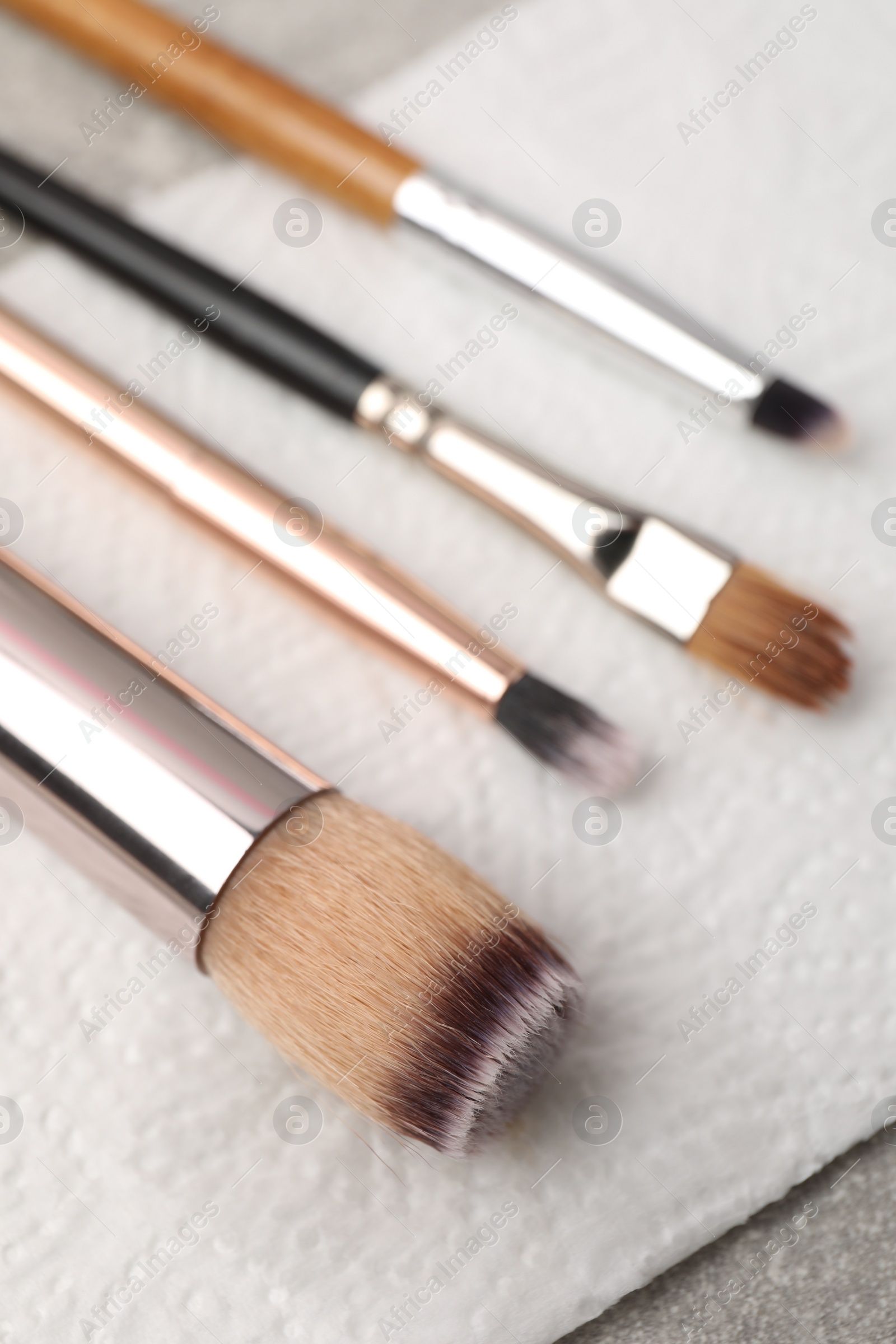 Photo of Clean makeup brushes with napkin on table, closeup