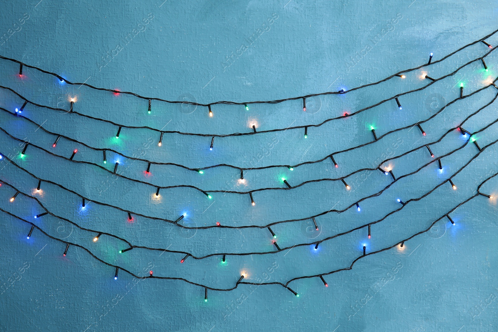 Photo of Beautiful bright Christmas lights on color background