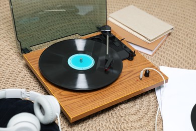 Photo of Stylish turntable with vinyl disc and headphones on carpet at home