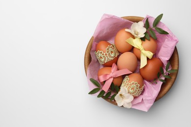 Photo of Easter eggs with colorful bows, twigs and flowers on white background, top view. Space for text