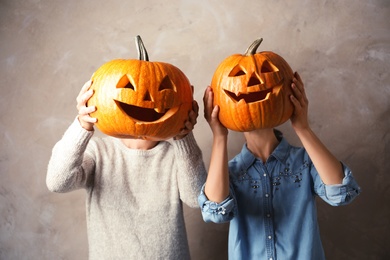 Photo of Women holding Halloween pumpkin head jack lanterns against color background