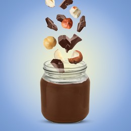 Image of Making yummy chocolate paste. Hazelnuts and pieces of chocolate falling into jar on light blue background