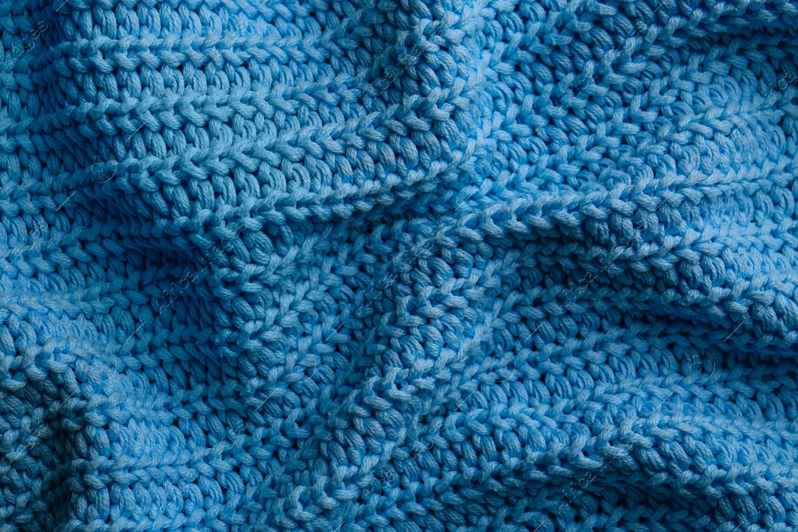 Photo of Beautiful light blue knitted fabric as background, top view