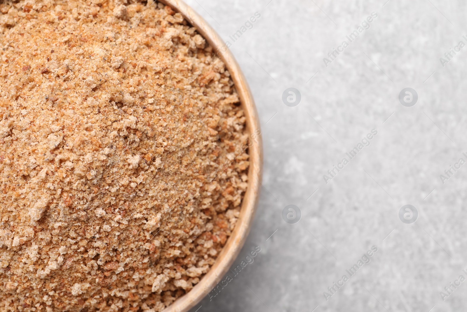 Photo of Fresh bread crumbs in bowl on grey table, top view. Space for text