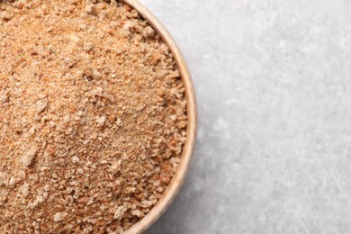 Fresh bread crumbs in bowl on grey table, top view. Space for text