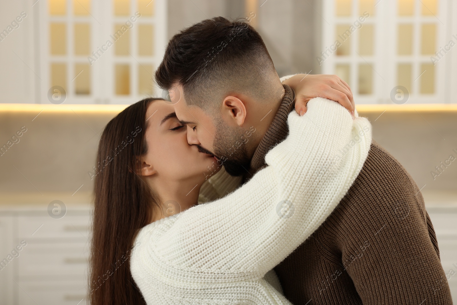 Photo of Affectionate young couple kissing and hugging in kitchen