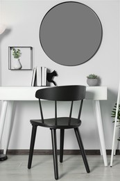 Photo of Stylish room interior with round mirror on white wall over desk