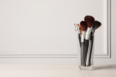 Set of professional makeup brushes on table against white background, space for text