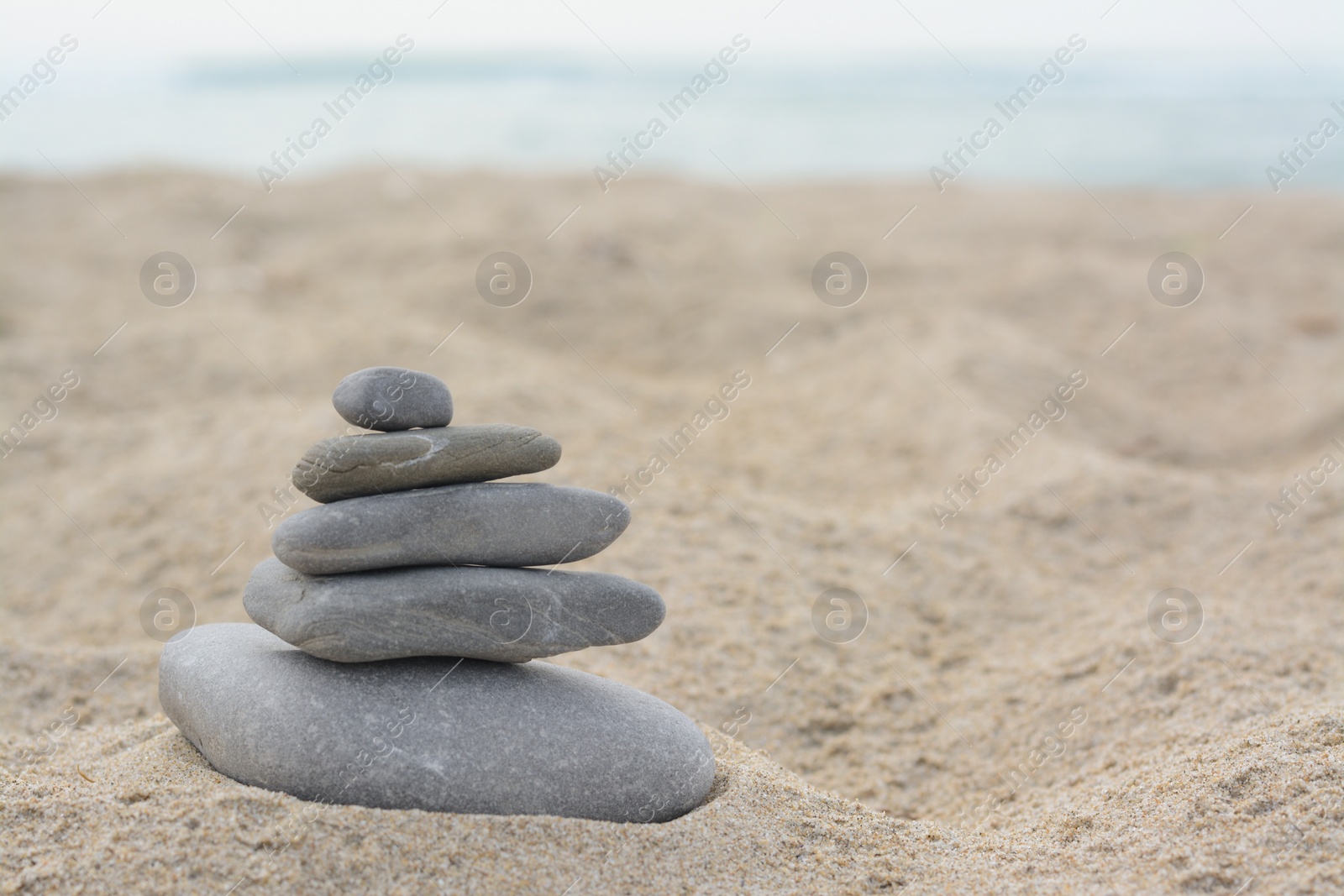 Photo of Stack of stones on sandy beach near sea, space for text