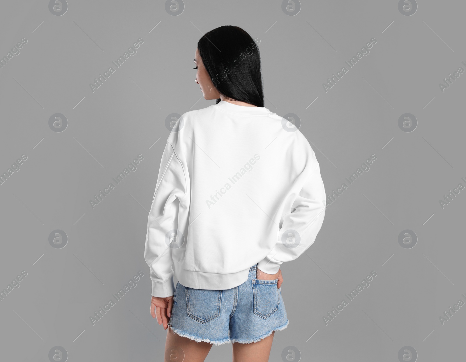 Photo of Young woman in sweater on grey background. Mock up for design