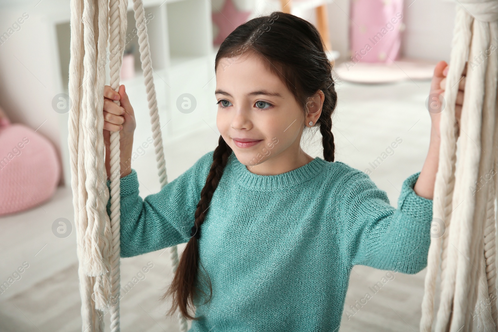 Photo of Cute little girl playing on swing at home