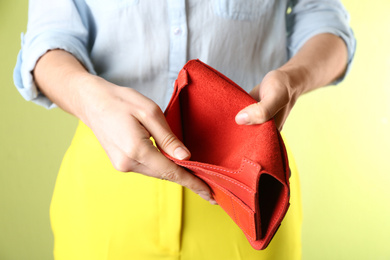 Photo of Woman showing empty wallet on light green background, closeup