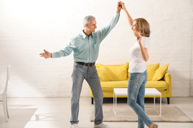 Photo of Happy senior couple dancing in living room