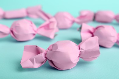 Photo of Candies in pink wrappers on light blue background, closeup