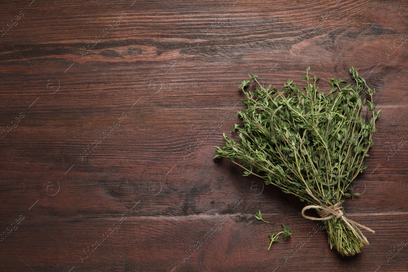 Photo of Bunch of aromatic thyme on wooden table, top view. Space for text