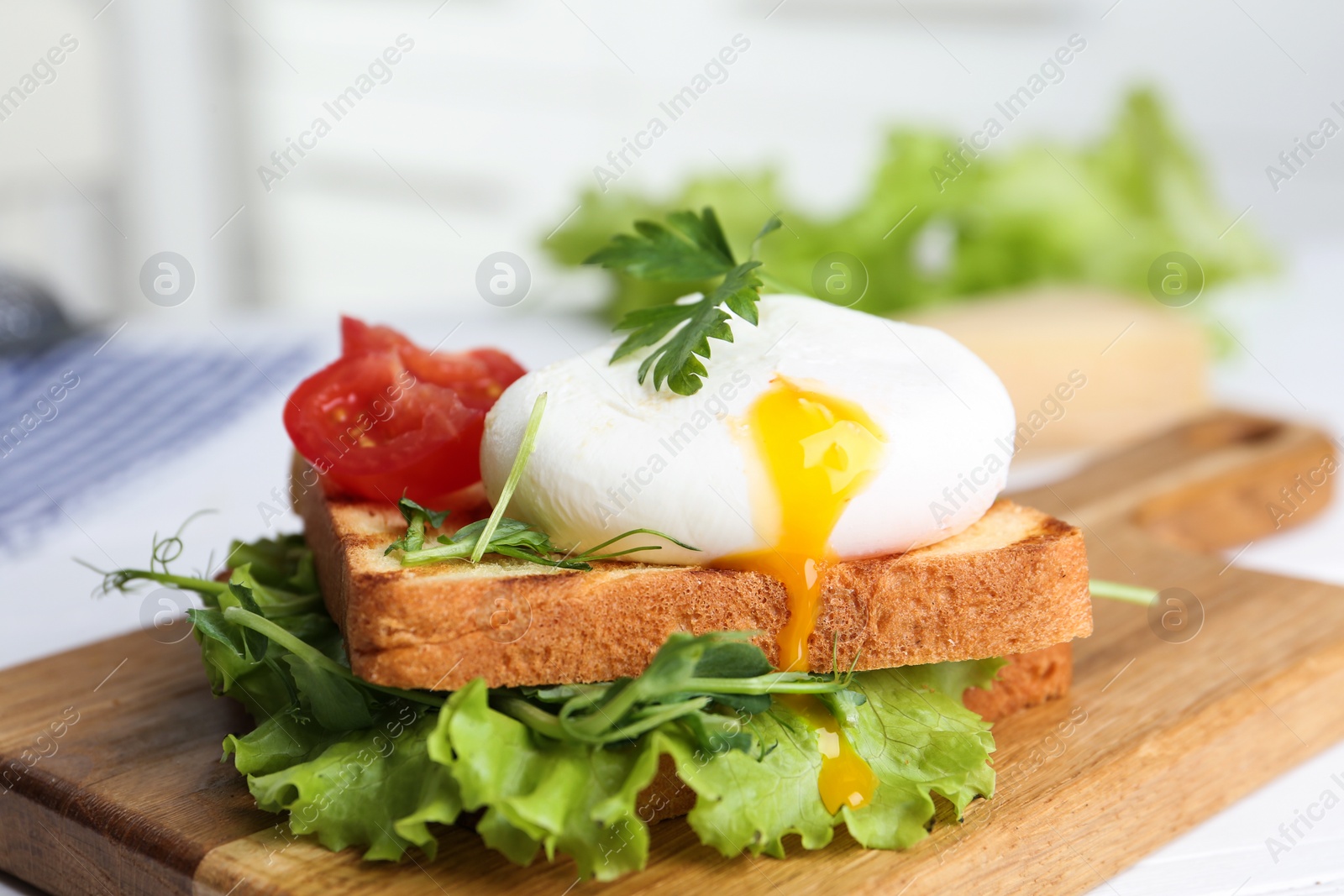 Photo of Delicious poached egg sandwich served on wooden board, closeup