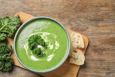 Photo of Tasty kale soup served on wooden table, flat lay