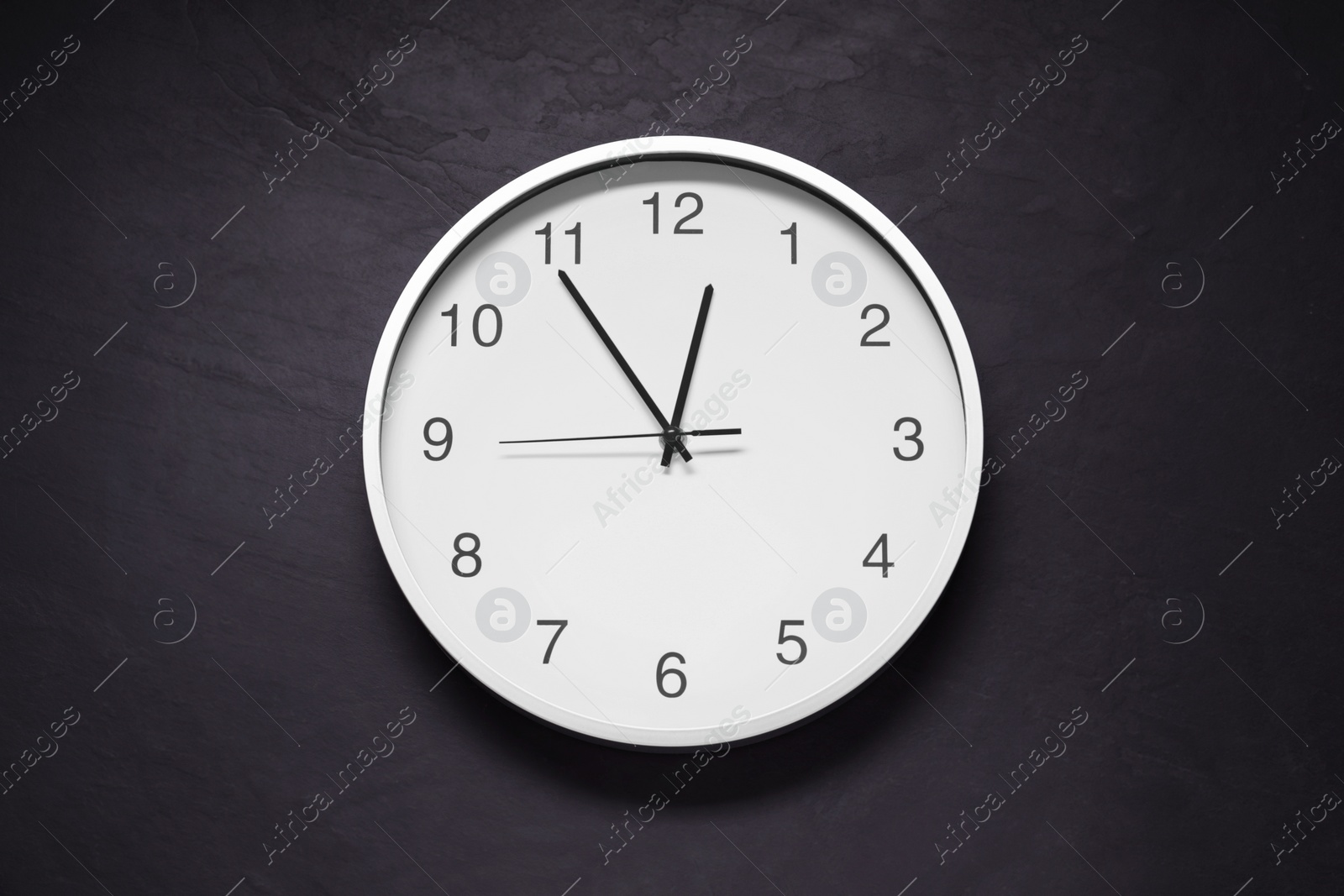 Photo of Stylish round clock on black table, top view. Interior element