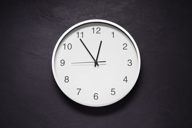 Photo of Stylish round clock on black table, top view. Interior element