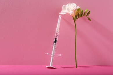 Photo of Cosmetology. Medical syringe and freesia flower on pink background