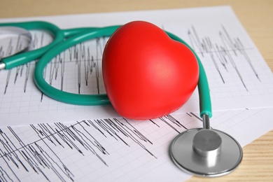 Stethoscope, red heart and cardiograms on table. Cardiology concept