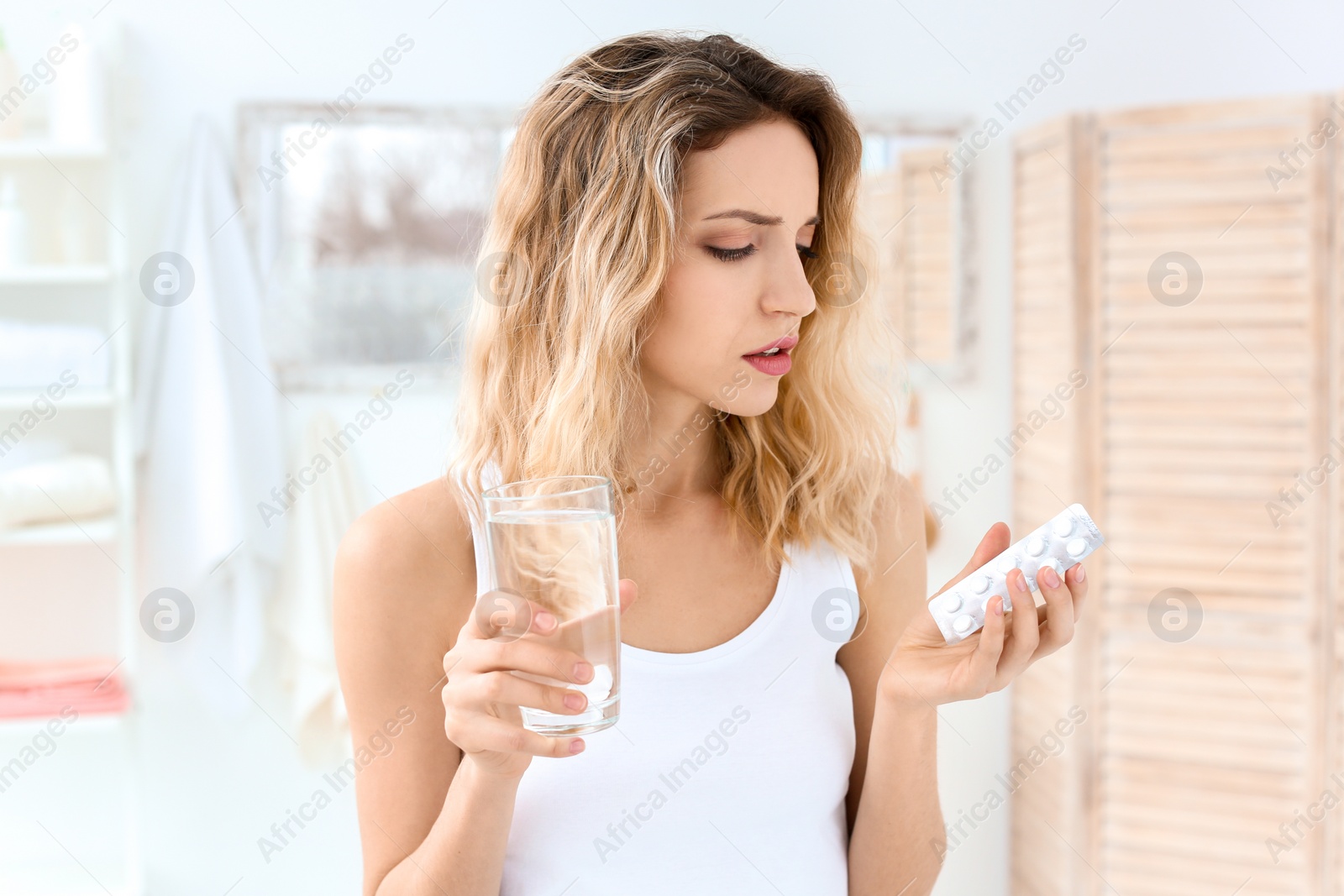 Photo of Young woman with pills and glass of water indoors