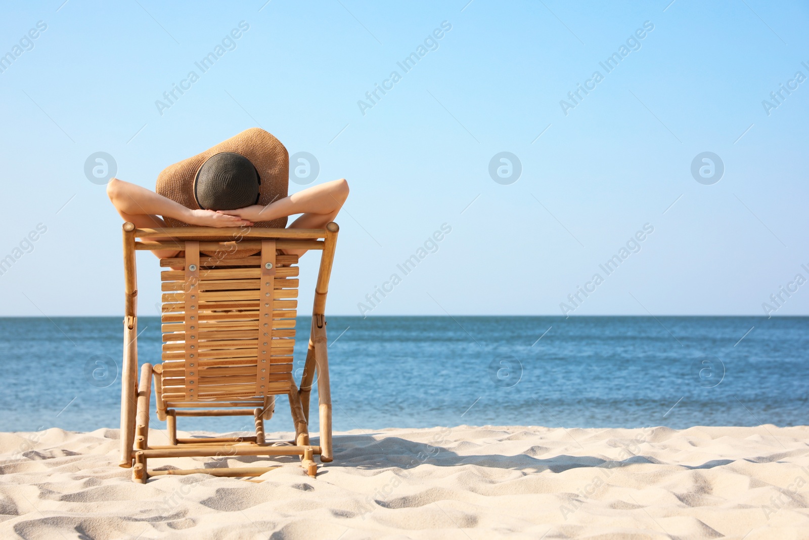 Photo of Young woman relaxing in deck chair on sandy beach