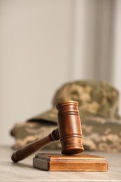 Photo of Law concept. Gavel and military uniform on wooden table, closeup. Space for text