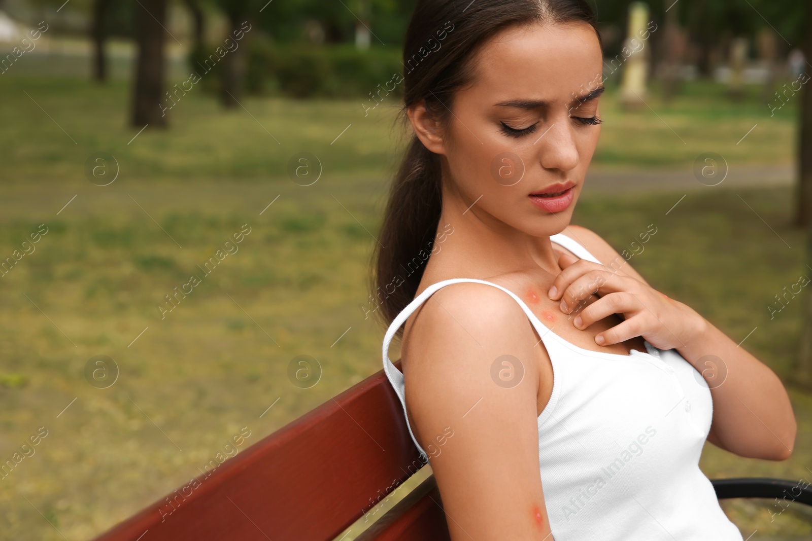 Photo of Woman scratching neck with insect bite in park. Space for text