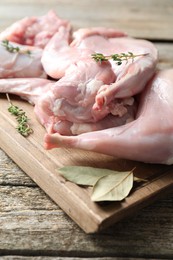 Photo of Fresh raw rabbit meat and spices on wooden table, closeup